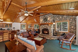 Ein gemütliches Lodge-Interieur mit Kamin aus Stein, Holzbalkendecke und Essbereich.