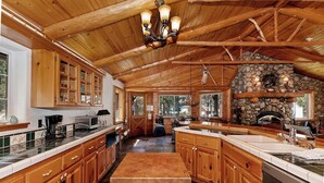 A spacious kitchen with wooden cabinets, a stone fireplace, and a large island.