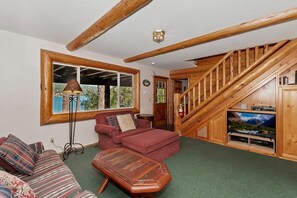 Ein gemütliches Wohnzimmer mit einer Holztreppe, einem Sofa, einem Couchtisch und einem Fernseher.