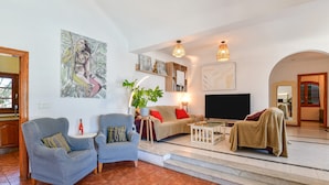 A living room with a sofa, two armchairs, a coffee table, a TV, and artwork on the walls. - Villa Alex with WiFi and Pool (Puerto del Carmen)