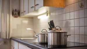 Une cuisine avec des casseroles en acier inoxydable sur le plan de travail, un range-couteaux et un pare-feu en carreaux.