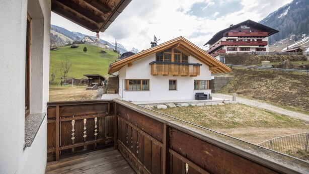 A hotel with a balcony, a view of a green hillside, and a mountain in the background. - Apartment “Bärental” in Beautiful Scenery with Mountain View, Wi-Fi & Garden (St.Jakob im Ahrntal)