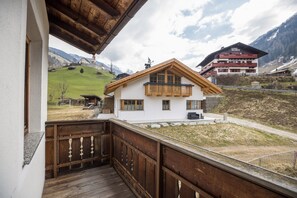 Un hôtel doté d’un balcon, offrant une vue sur une colline verdoyante et sur une montagne en arrière-plan.