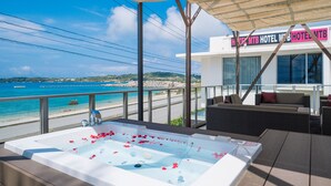 A hotel balcony with a hot tub, outdoor seating, and a view of the beach and ocean. - HOTEL Churabeach (Motobu)