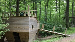 Una casita de juegos de madera con una escalera y una rueda.