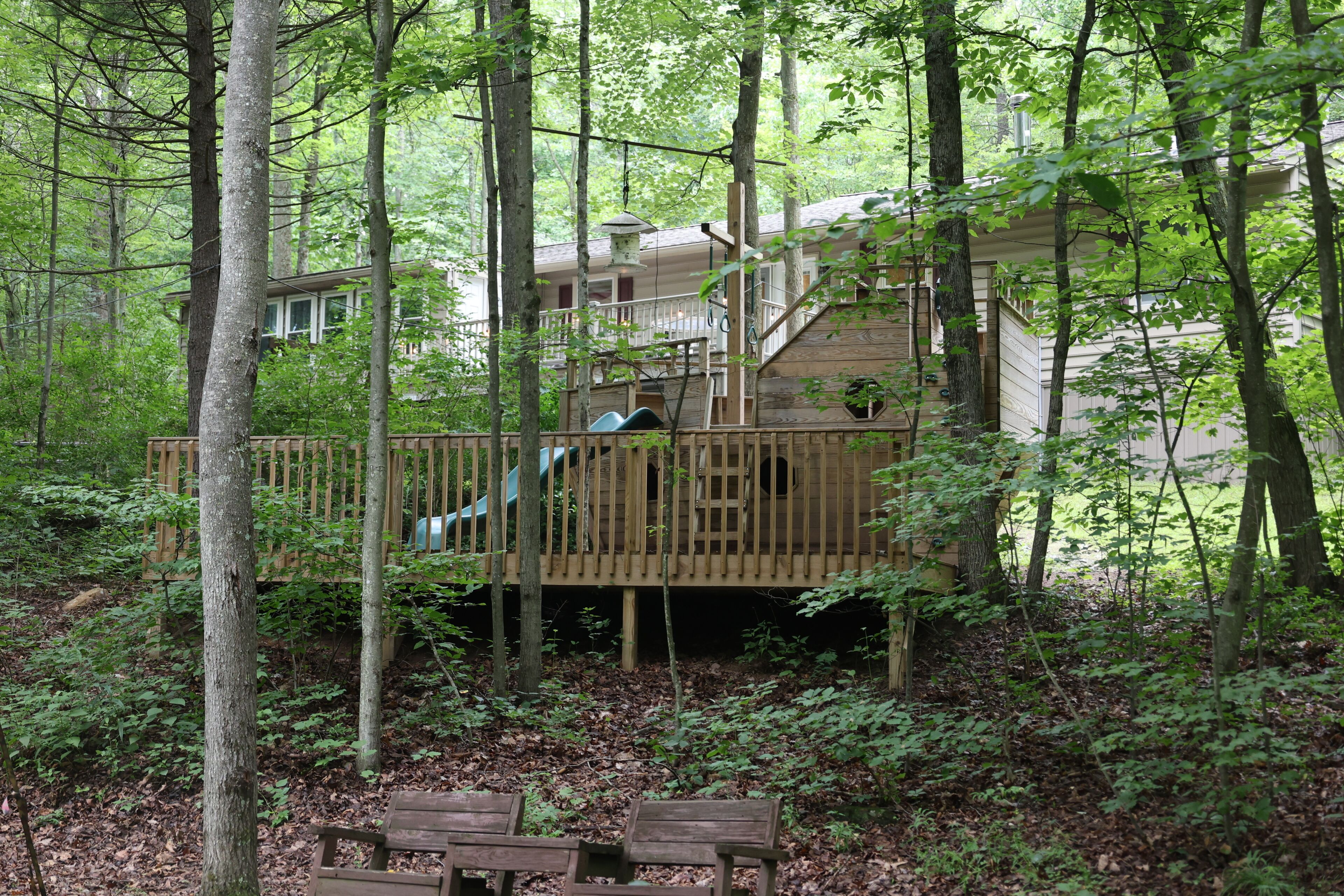 A wooden deck with a staircase leading to a building surrounded by trees.