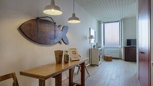 Un interior modern amb una taula de fusta, llums penjants, una gran decoració mural amb forma de peix i vista al mar per la finestra.