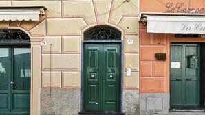 Fachada d'un edifici amb portes numerades, una bústia a la vista i un petit senyal que indica una zona de videovigilància.