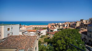 Eine Küstenstadt mit Häusern mit Terrakotta-Dächern, einem klaren blauen Himmel und Blick auf das Meer.