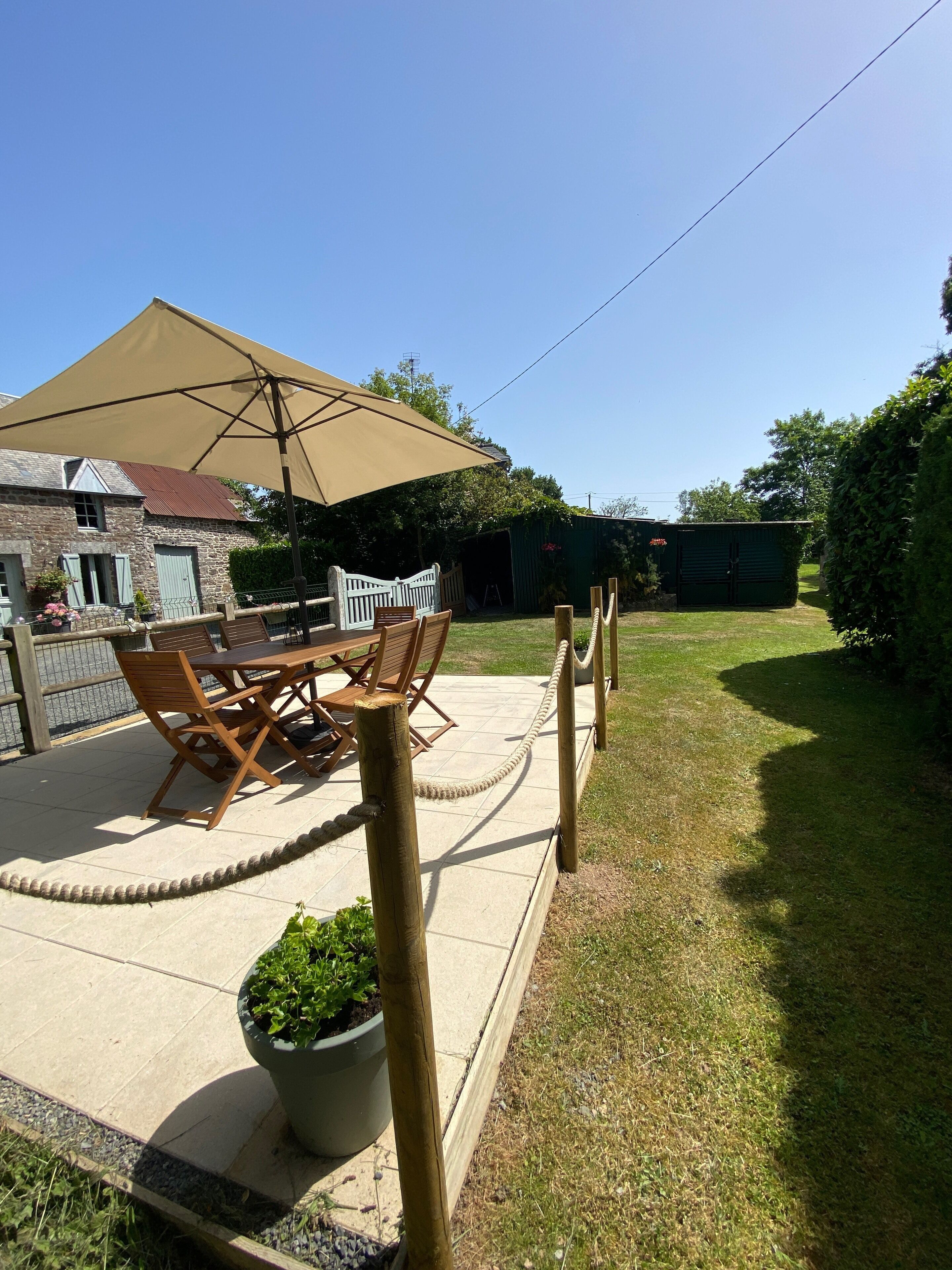 A patio with a table and chairs, a large umbrella, and a wooden fence.