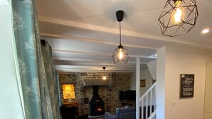 Zona pranzo con tavolo di legno apparecchiato per quattro persone, camino in pietra e scala che conduce a un altro piano.
