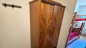 A wooden wardrobe with a marble-like pattern, a metal handle, and a carpeted floor.