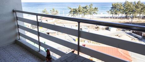 Un balcon avec vue sur la mer, une bouteille de bière et des en-cas sur une table.