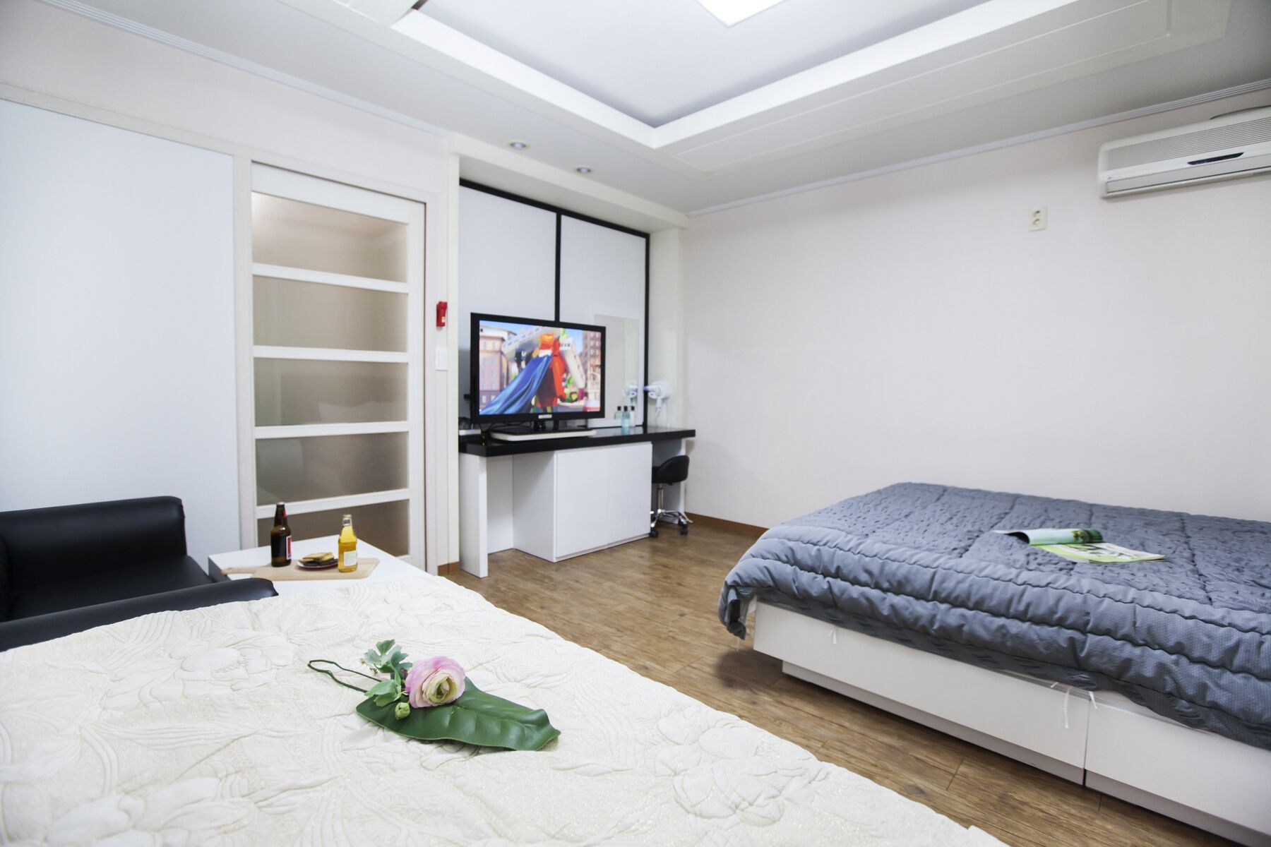 A modern bedroom with a bed, a desk, a TV, and a wardrobe.