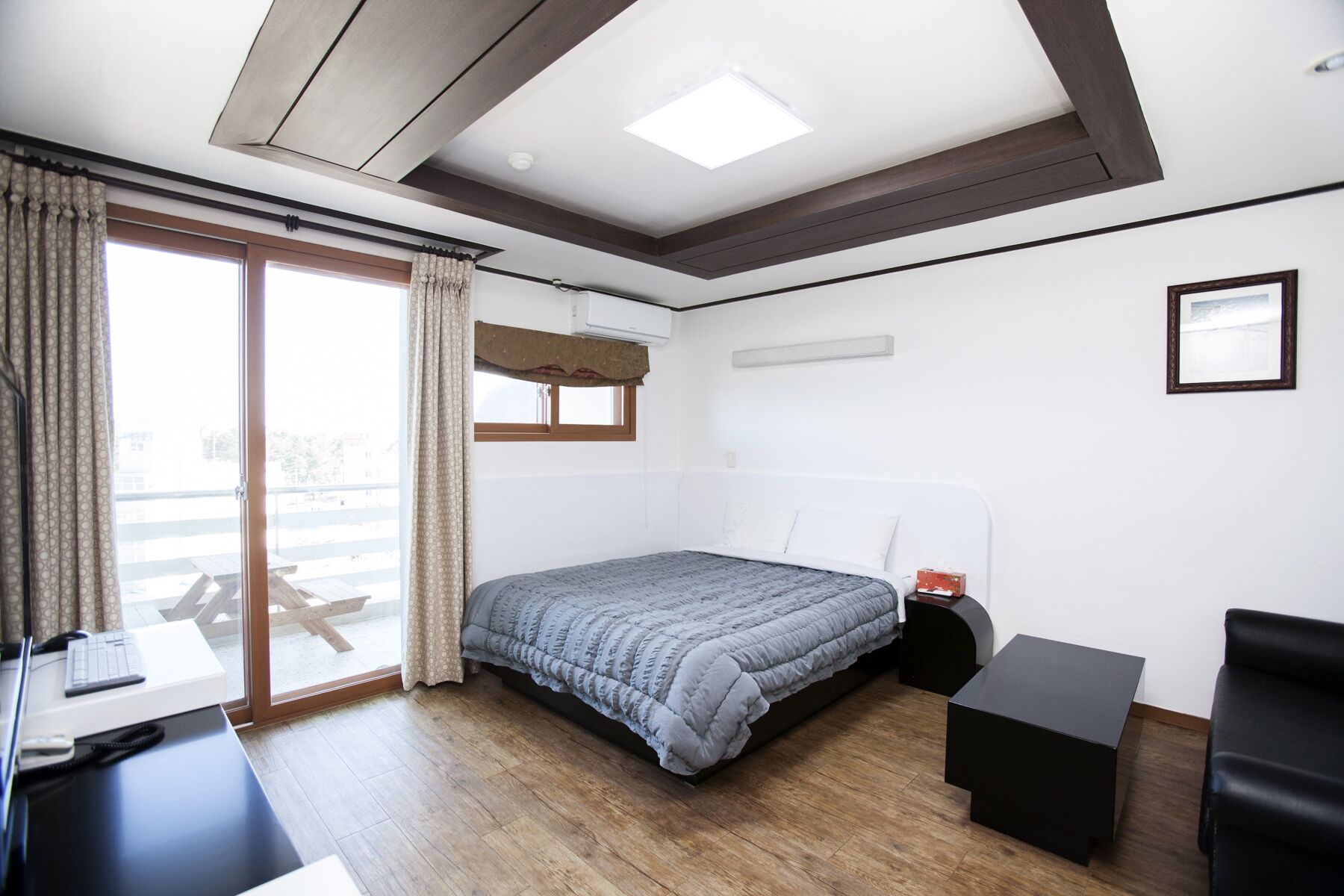 A modern bedroom with a large bed, a desk, and a chair.