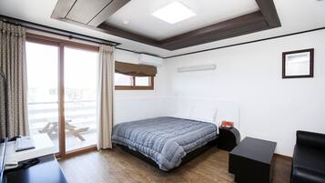 A modern bedroom with a large bed, a desk, and a chair.