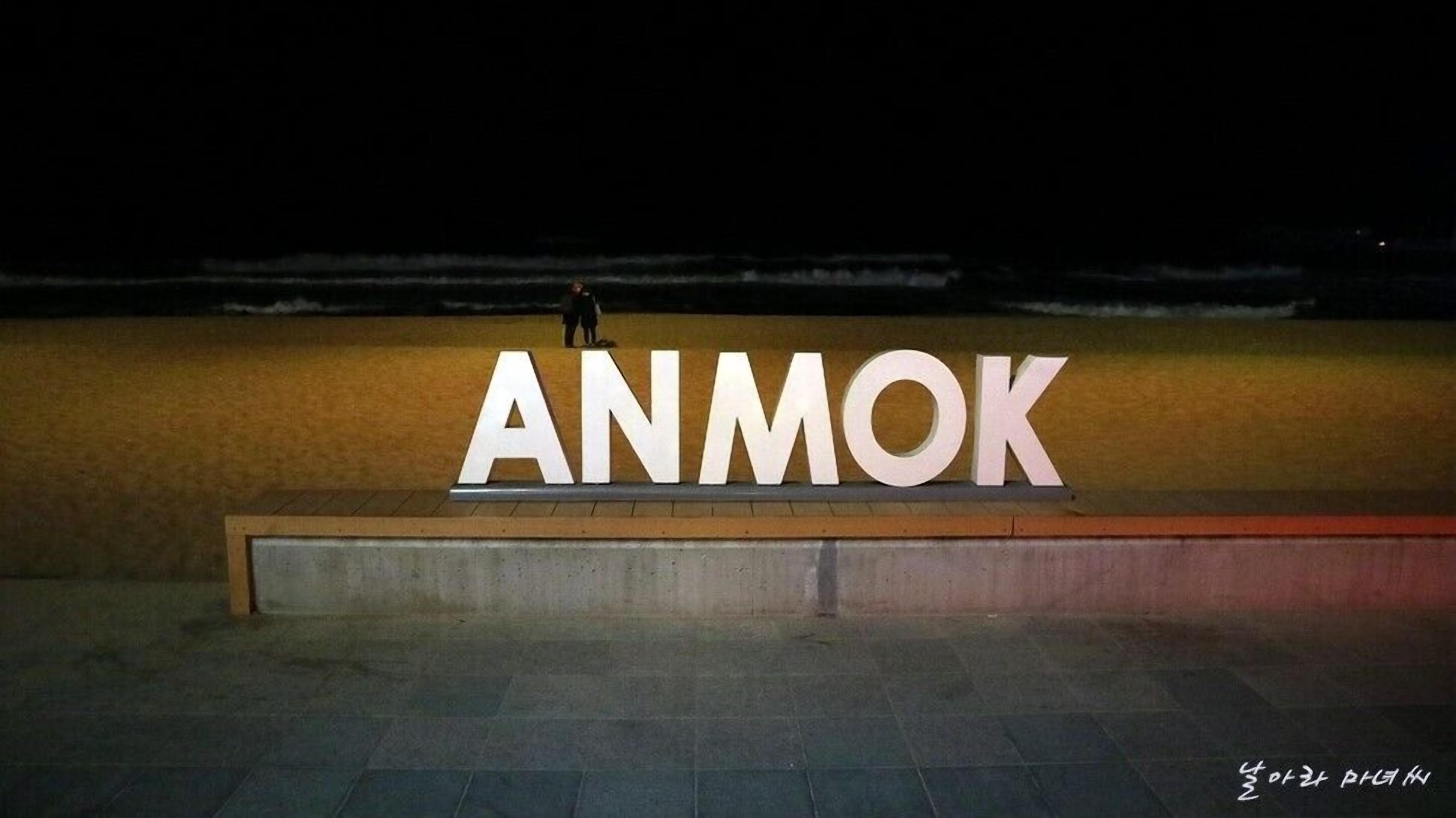 A large illuminated sign with the word "ANMOK" against a dark background.