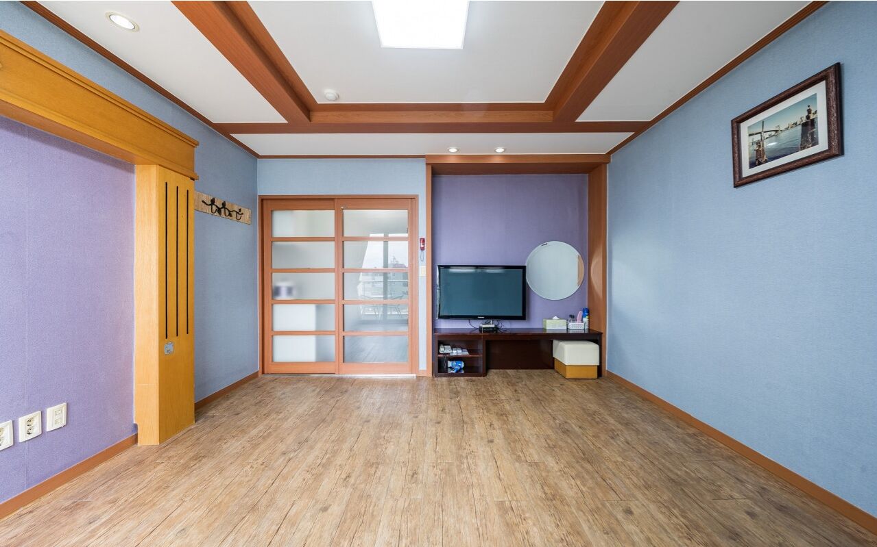 A room with a wooden floor, a sliding glass door, a television, and a framed picture on the wall.