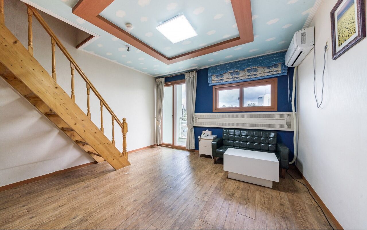 A room with a wooden staircase, a window with curtains, a radiator, and a white bench.