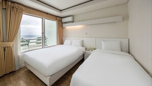 Une chambre d’hôtel avec deux lits, une grande fenêtre avec des rideaux, une table de chevet et un climatiseur fixé au mur.
