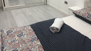 A bedroom with a large mirror, a bed with patterned bedding, a bedside table, and a chair. - Nice 2 Bed Independent Annex in High Wycombe (High Wycombe)