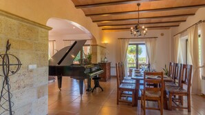 Un'ampia sala da pranzo con un pianoforte a coda, un tavolo in legno e sedie.
