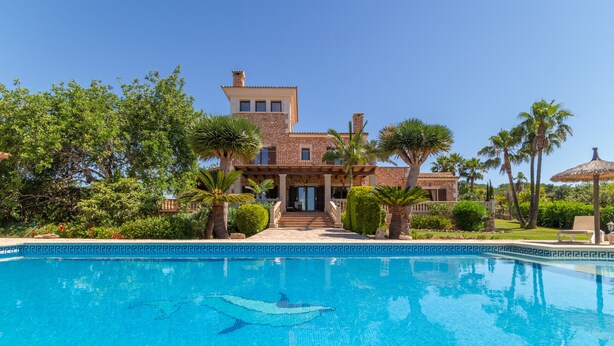 Una grande casa con una piscina di fronte.