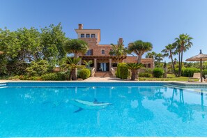 Uma casa grande com piscina em frente.
