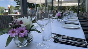 An outdoor dining area with tables set for a meal, clear glassware, and a view of the sky and trees. - Villa Bałtycka (Gdansk)