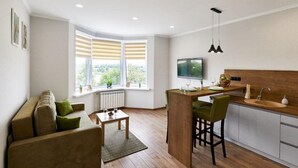 A modern kitchen with a dining area, a TV, and a window with blinds. - PaulMarie Apartments on Mayakovskogo 35 (Minsk)