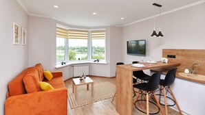 A modern living room with a sofa, a dining table, and a kitchen area with a sink and chairs. - PaulMarie Apartments on Mayakovskogo 35 (Minsk)