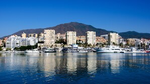 A marina with several yachts and boats docked, surrounded by high-rise buildings and a mountain in the background. - Appartement Palmeras Puerto Paraiso Estepona (Estepona)
