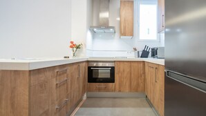 A modern kitchen with wooden cabinets, a stainless steel range hood, a built-in oven, and a refrigerator.