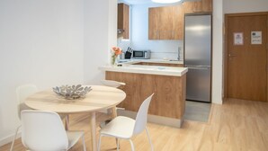 A modern kitchen with a central island, white chairs, and a stainless steel refrigerator.