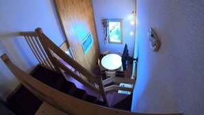 Un escalier en bois mène à une pièce où se trouvent une petite table et une fenêtre.