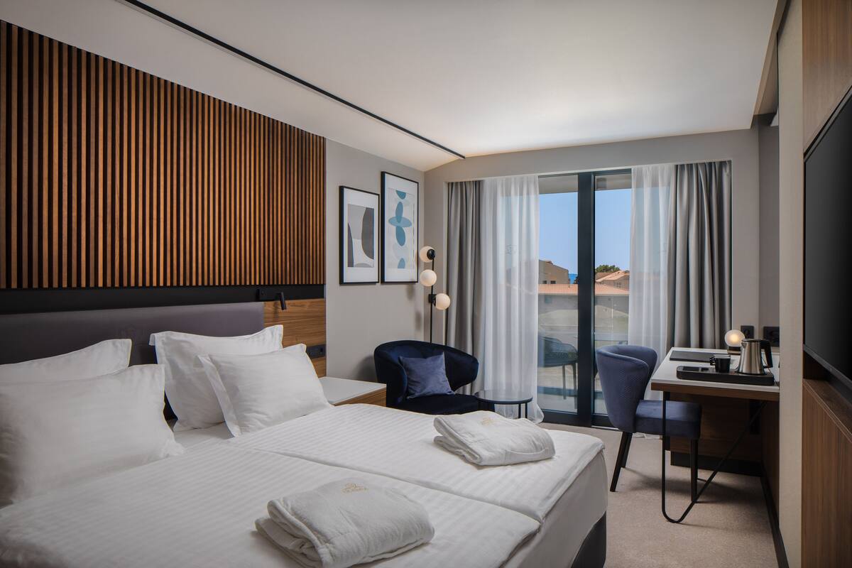 A hotel room with a large bed, a desk, a chair, and a TV.