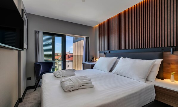 A modern hotel room with a large bed, a desk, and a chair. - Boutique hotel Noemia (Baska Voda)