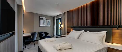 A modern hotel room with a large bed, a desk, and a chair.