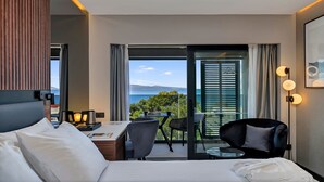 A modern hotel room with a bed, a desk with a laptop, a chair, and a view of the sea. - Boutique hotel Noemia (Baska Voda)