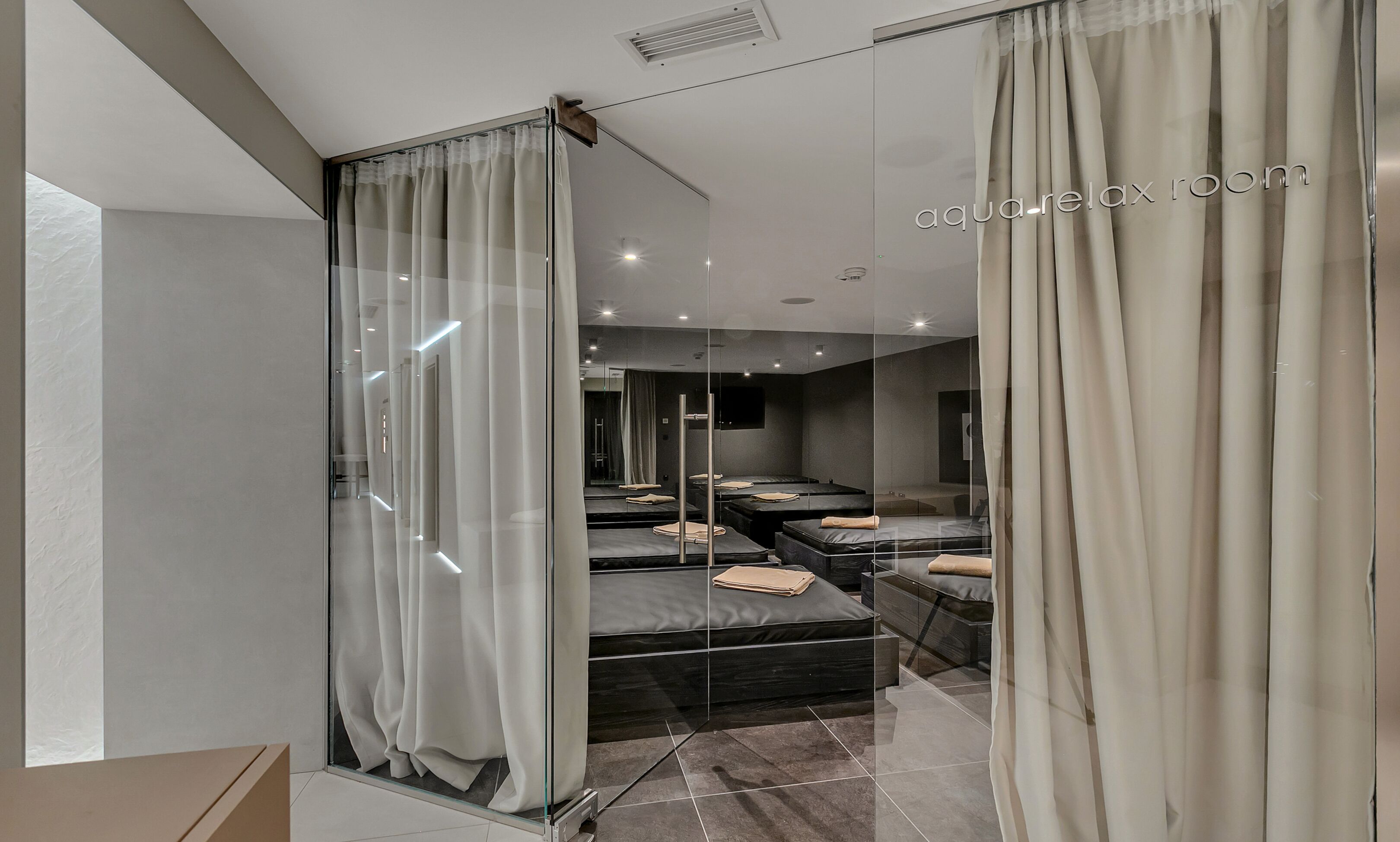 A modern bathroom with a glass partition, a large mirror, and a vanity with a sink.