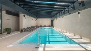 An indoor swimming pool with a glass ceiling, tiled walls, and lounge chairs along the sides. - Boutique hotel Noemia (Baska Voda)