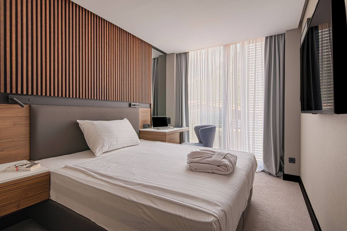 A modern hotel room with a large bed, a desk, and a chair.