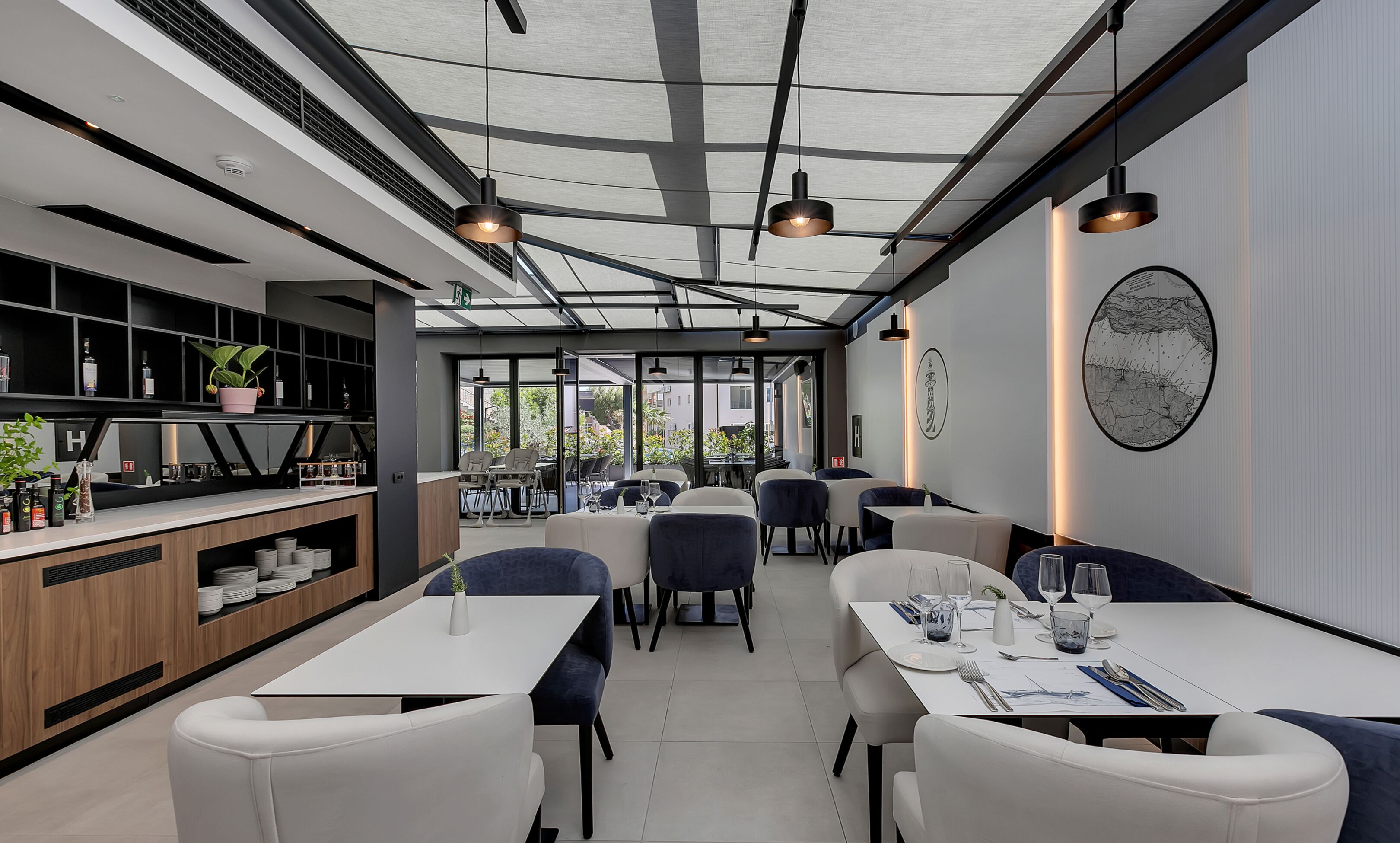 Interior moderno de restaurante con techo alto, vigas a la vista y luz natural proveniente de grandes ventanales.