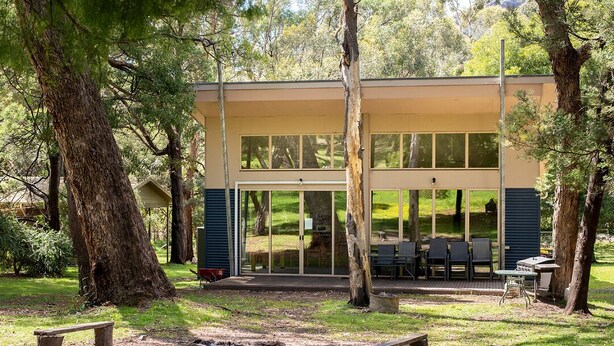 A modern building with large windows, surrounded by trees and a grassy area with benches. - "Parkview West" hosted by Halls Gap Accommodation (Halls Gap)
