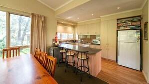 A modern kitchen with a large island, bar stools, and a dining table with chairs. - "Parkview West" hosted by Halls Gap Accommodation (Halls Gap)