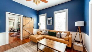 A living room with a sectional sofa, a wooden coffee table, and a patterned rug. - Downtown Victorian Near Forsyth, Nightlife, Enmarket Arena by Lucky Savannah (SAVANNAH)