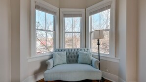 A room with a light blue sofa, three windows, and a floor lamp. - Downtown Victorian Near Forsyth, Nightlife, Enmarket Arena by Lucky Savannah (SAVANNAH)