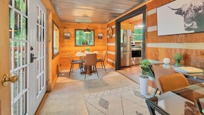 Un intérieur en bois comprenant un coin repas, une cuisine et un grand tableau représentant un taureau.