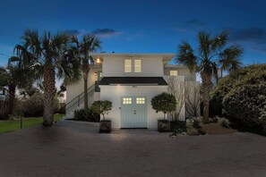 A two-story house with a light blue door, a staircase, and a driveway.