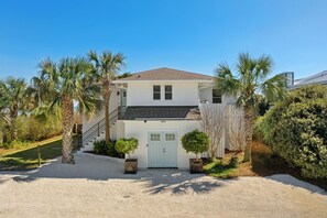 A two-story house with a white exterior, a front door, and a staircase leading to the second floor. - East Arctic Avenue 0603 - Sunshine By The Sea (Folly Beach)